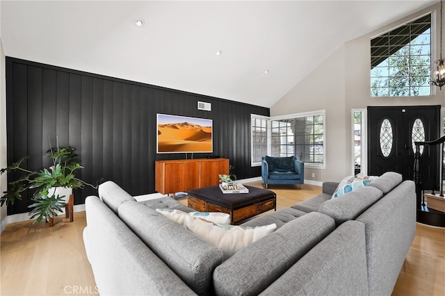 living area with high vaulted ceiling, an accent wall, baseboards, and a wealth of natural light