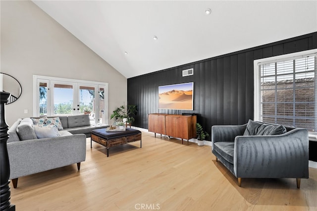living area featuring visible vents, an accent wall, high vaulted ceiling, recessed lighting, and light wood-style flooring