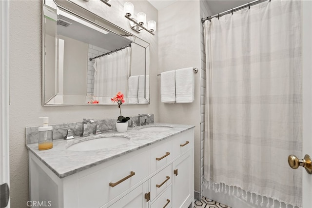 full bath featuring visible vents, a sink, curtained shower, and double vanity