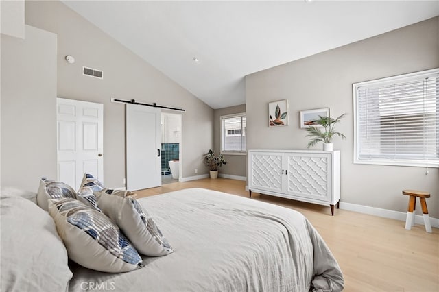 bedroom with visible vents, wood finished floors, a barn door, baseboards, and high vaulted ceiling