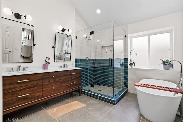 bathroom with double vanity, a freestanding bath, tile patterned floors, a sink, and a stall shower