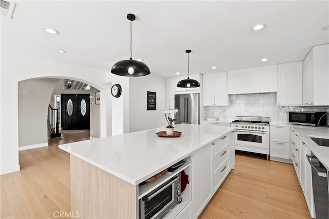 kitchen featuring recessed lighting, arched walkways, backsplash, and high end appliances