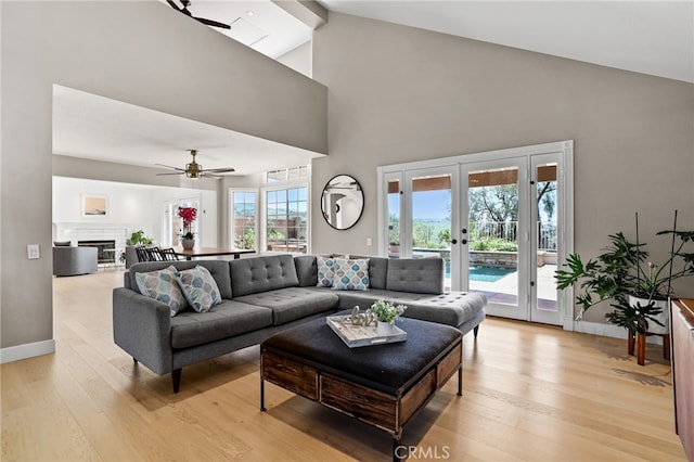 living room featuring ceiling fan, french doors, high vaulted ceiling, and light wood-type flooring