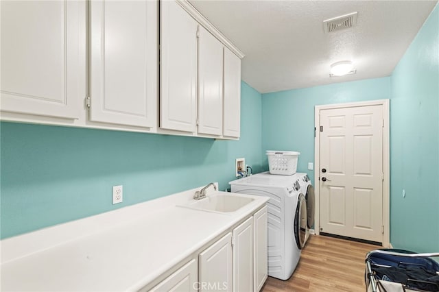 32701 Juniper Berry Dr, Winchester, CA 92596 - laundry area with cabinet space, washer and clothes dryer, light wood-style flooring, and a textured ceiling