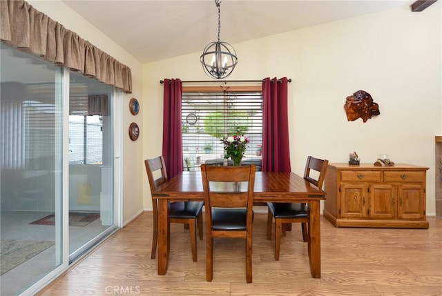 dining room with plenty of natural light, vaulted ceiling, light wood-style flooring, and a notable chandelier