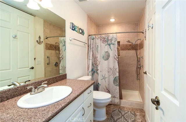 full bathroom featuring vanity, tile patterned floors, a tile shower, and toilet