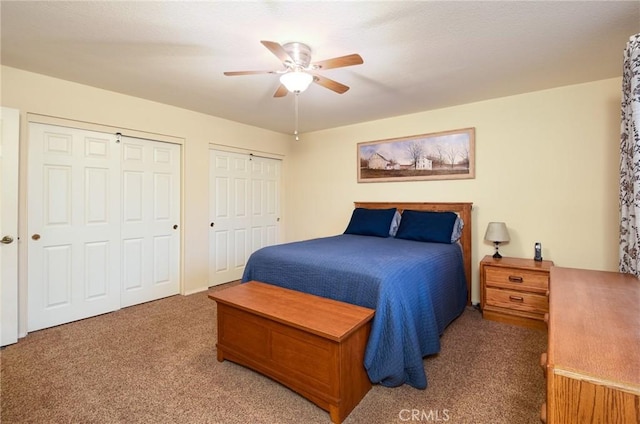 carpeted bedroom featuring multiple closets and a ceiling fan