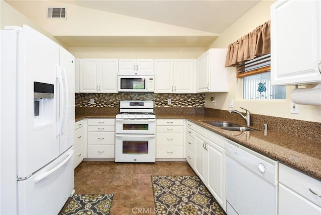 kitchen featuring visible vents, lofted ceiling, white appliances, white cabinets, and a sink