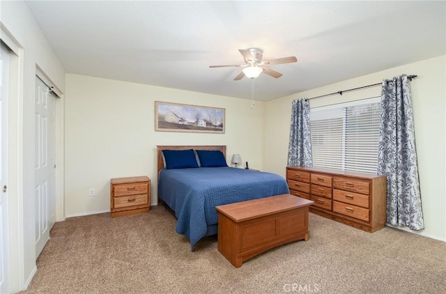 bedroom with a closet, baseboards, light carpet, and a ceiling fan
