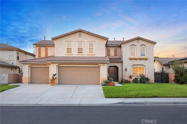 mediterranean / spanish-style home with a tile roof, driveway, a gate, and stucco siding