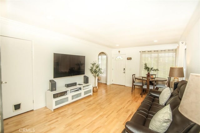living area with crown molding, arched walkways, and wood finished floors