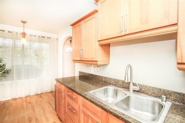 25957 Via Pera Unit C4, Mission Viejo, CA 92691 - kitchen featuring decorative light fixtures, arched walkways, light wood-type flooring, a sink, and dark stone countertops