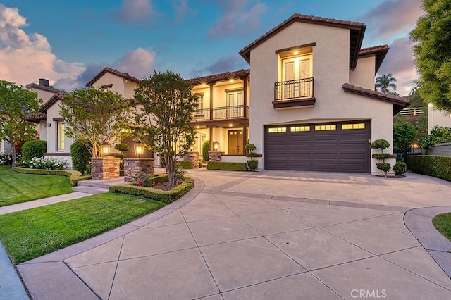 mediterranean / spanish house featuring a yard, a balcony, concrete driveway, an attached garage, and stucco siding