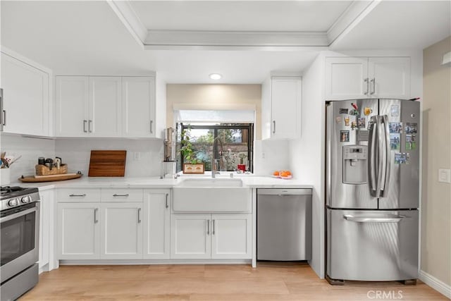 kitchen featuring a sink, white cabinetry, appliances with stainless steel finishes, and ornamental molding