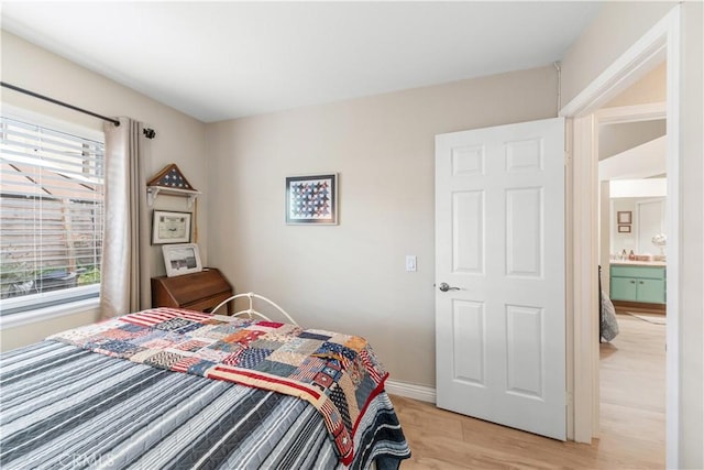 bedroom featuring baseboards, multiple windows, and light wood-type flooring