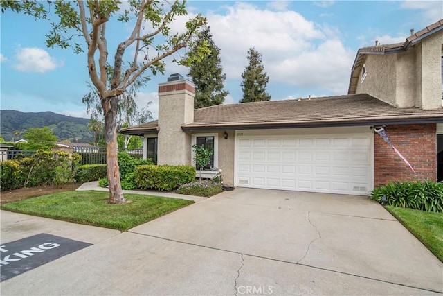 view of front of property featuring driveway, a chimney, fence, a mountain view, and an attached garage