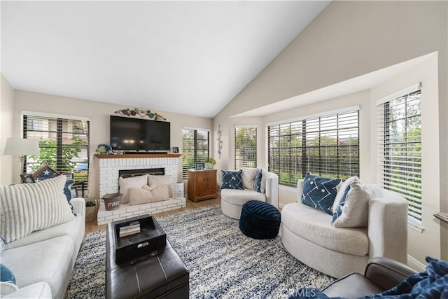 living room with a brick fireplace, a healthy amount of sunlight, and high vaulted ceiling
