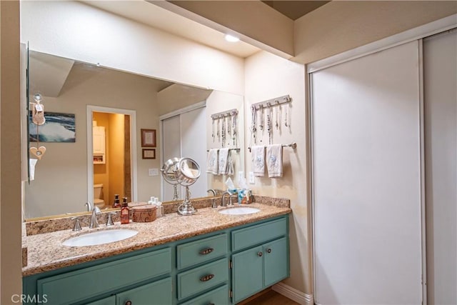 full bathroom with a sink, toilet, and double vanity