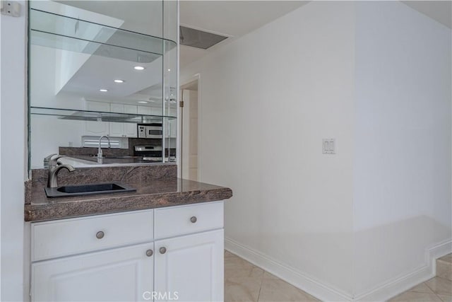 bar with a sink, baseboards, light marble finish flooring, range, and recessed lighting