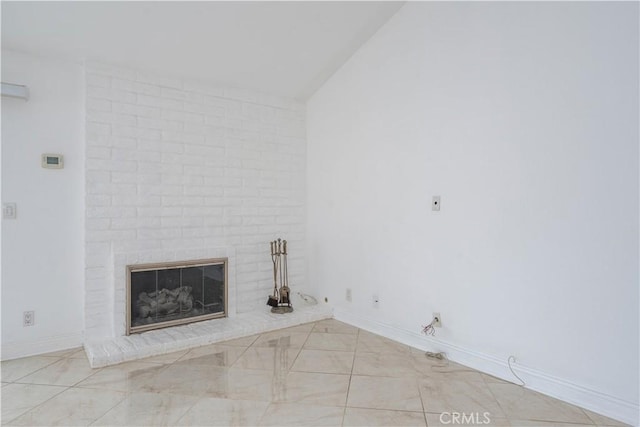 unfurnished living room featuring lofted ceiling, a fireplace, and baseboards