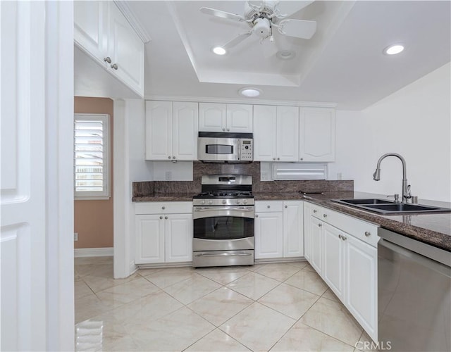 kitchen with appliances with stainless steel finishes, a sink, white cabinets, a raised ceiling, and recessed lighting