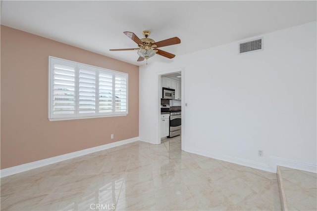 unfurnished room with ceiling fan and baseboards