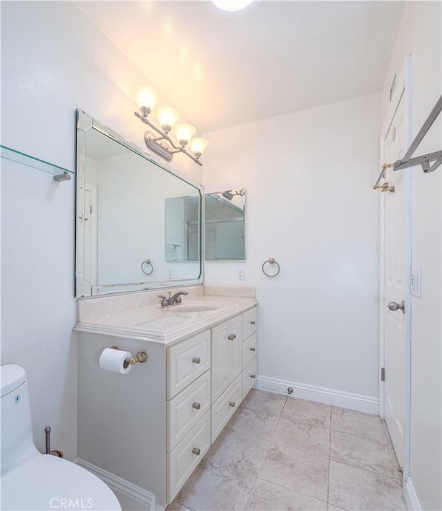 bathroom with toilet, vanity, marble look tiles, and baseboards