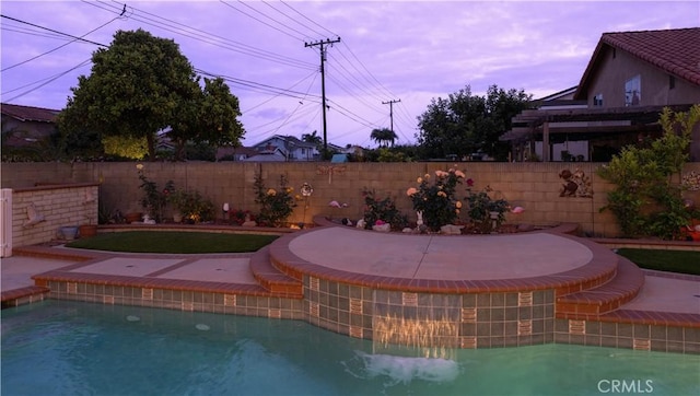 view of pool featuring fence and a pool with connected hot tub