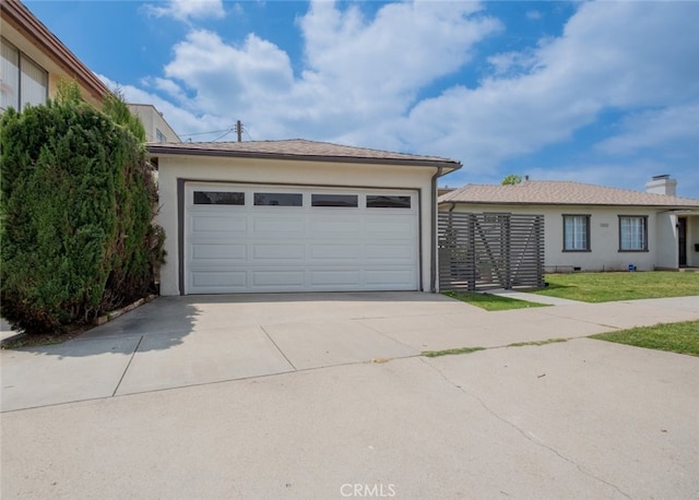 view of front of house featuring a garage, stucco siding, fence, and concrete driveway