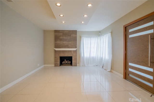 unfurnished living room featuring recessed lighting, baseboards, light tile patterned floors, and a tile fireplace