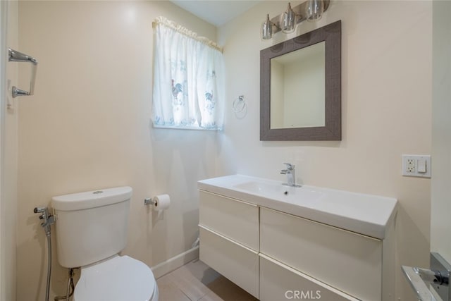 bathroom featuring toilet, baseboards, and vanity