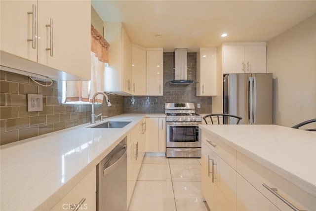 kitchen featuring wall chimney range hood, a sink, light countertops, stainless steel appliances, and light tile patterned floors