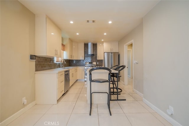 kitchen with wall chimney range hood, backsplash, visible vents, appliances with stainless steel finishes, and a sink