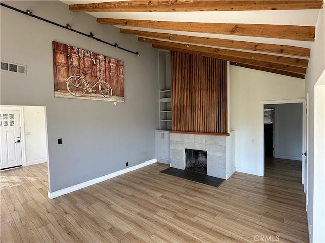 unfurnished living room featuring visible vents, baseboards, a tile fireplace, and light wood-type flooring