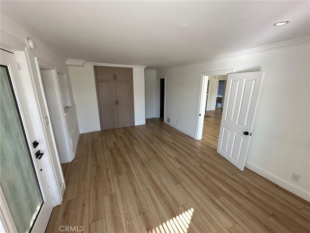 unfurnished bedroom featuring crown molding, baseboards, a closet, and light wood finished floors