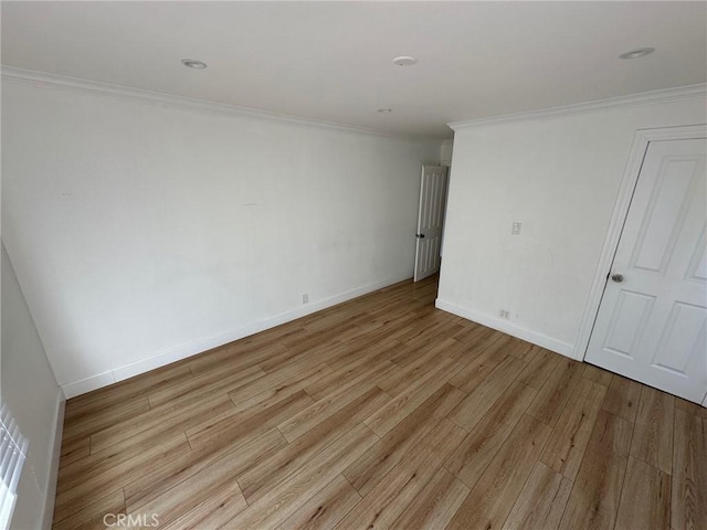 empty room featuring light wood-style floors, ornamental molding, and baseboards