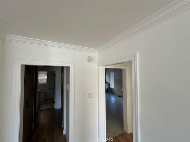 corridor featuring baseboards, ornamental molding, and wood finished floors