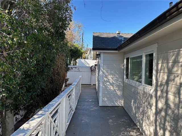 view of home's exterior with fence and a shingled roof
