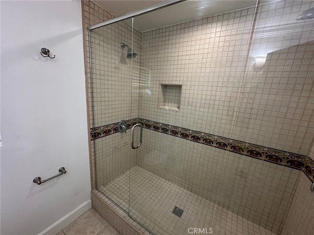 full bathroom featuring tile patterned floors, baseboards, and a stall shower