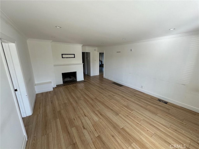 unfurnished living room featuring visible vents, a fireplace with flush hearth, and light wood-style flooring