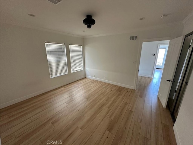 unfurnished room featuring visible vents, light wood-style flooring, crown molding, and baseboards