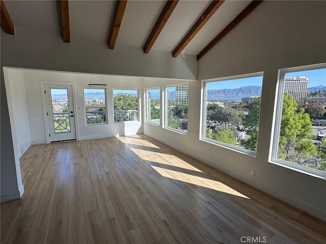unfurnished sunroom featuring baseboards, a deck with mountain view, wood finished floors, and a wealth of natural light