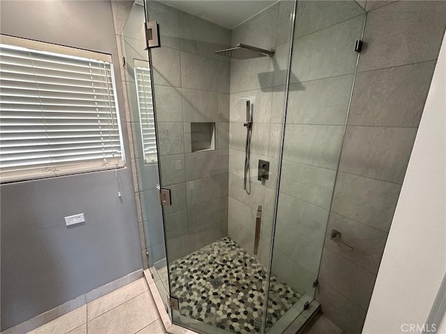 bathroom featuring baseboards, tile patterned flooring, and a shower stall