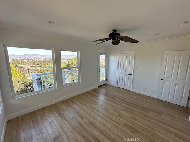 empty room with baseboards, ceiling fan, and light wood-type flooring