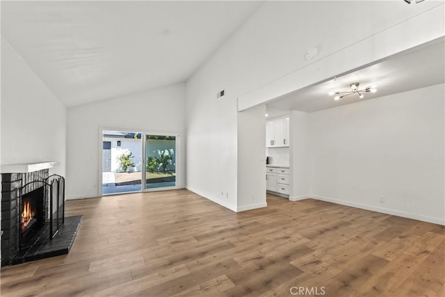 unfurnished living room with light wood-style floors, baseboards, a brick fireplace, and high vaulted ceiling
