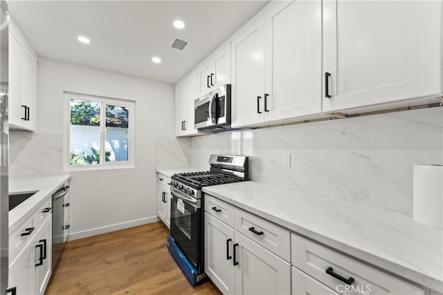 kitchen with visible vents, light wood-type flooring, white cabinetry, tasteful backsplash, and stainless steel appliances