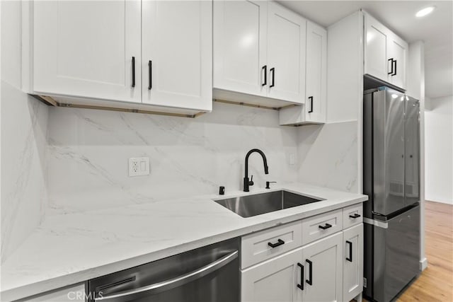 kitchen with light stone counters, a sink, white cabinetry, and stainless steel appliances