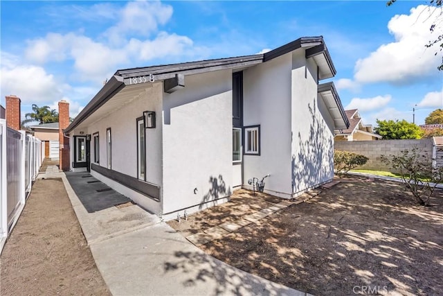 view of side of home featuring a fenced backyard and stucco siding