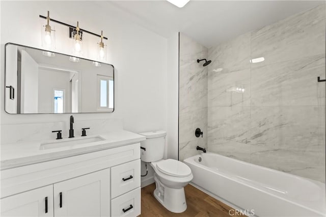 bathroom featuring toilet, washtub / shower combination, wood finished floors, and vanity