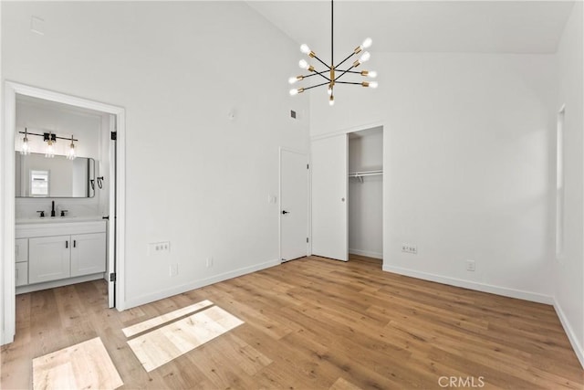 unfurnished bedroom with a notable chandelier, a sink, light wood finished floors, baseboards, and a closet